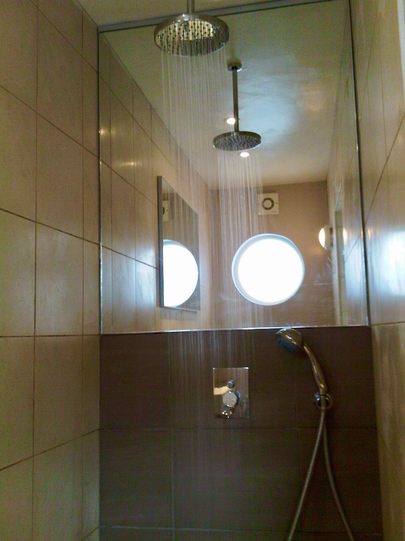Room four's en-suite showing rainfall shower head, mirror and round pothole window.